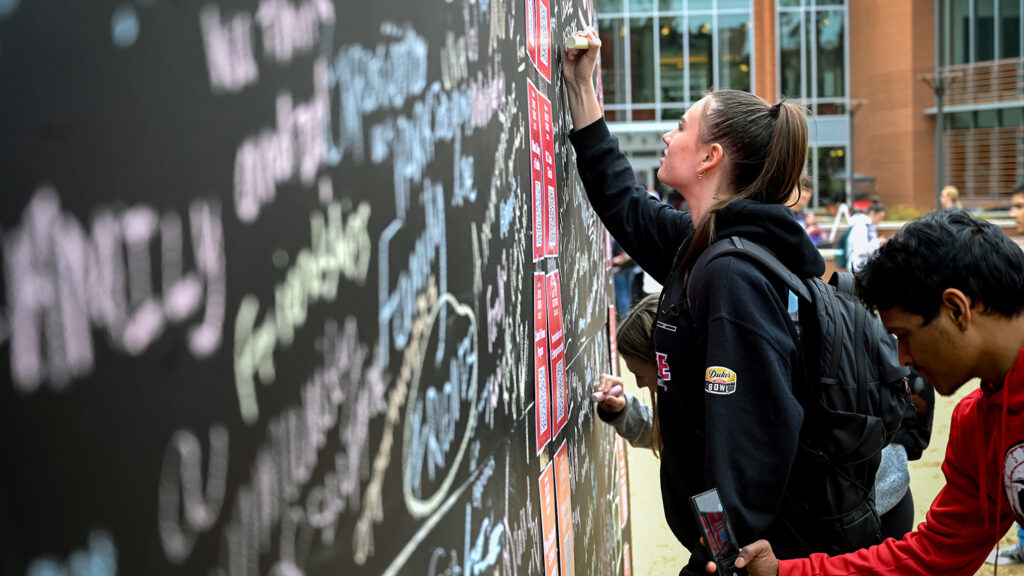 Staff, faculty and students all participated in NC State's annual Day of Giving; which centered around student events on both main and Centennial campus. Photo by Marc Hall Students sign a wall expressing what the love about NC State on Stafford Commons.