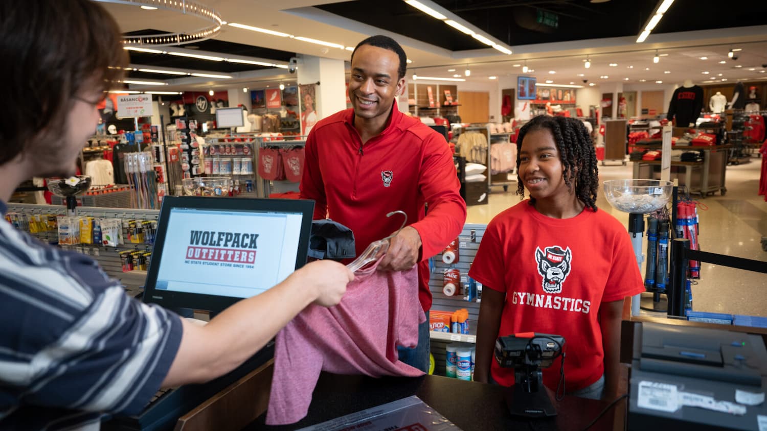 A father and daughter buy Wolfpack merchandise.